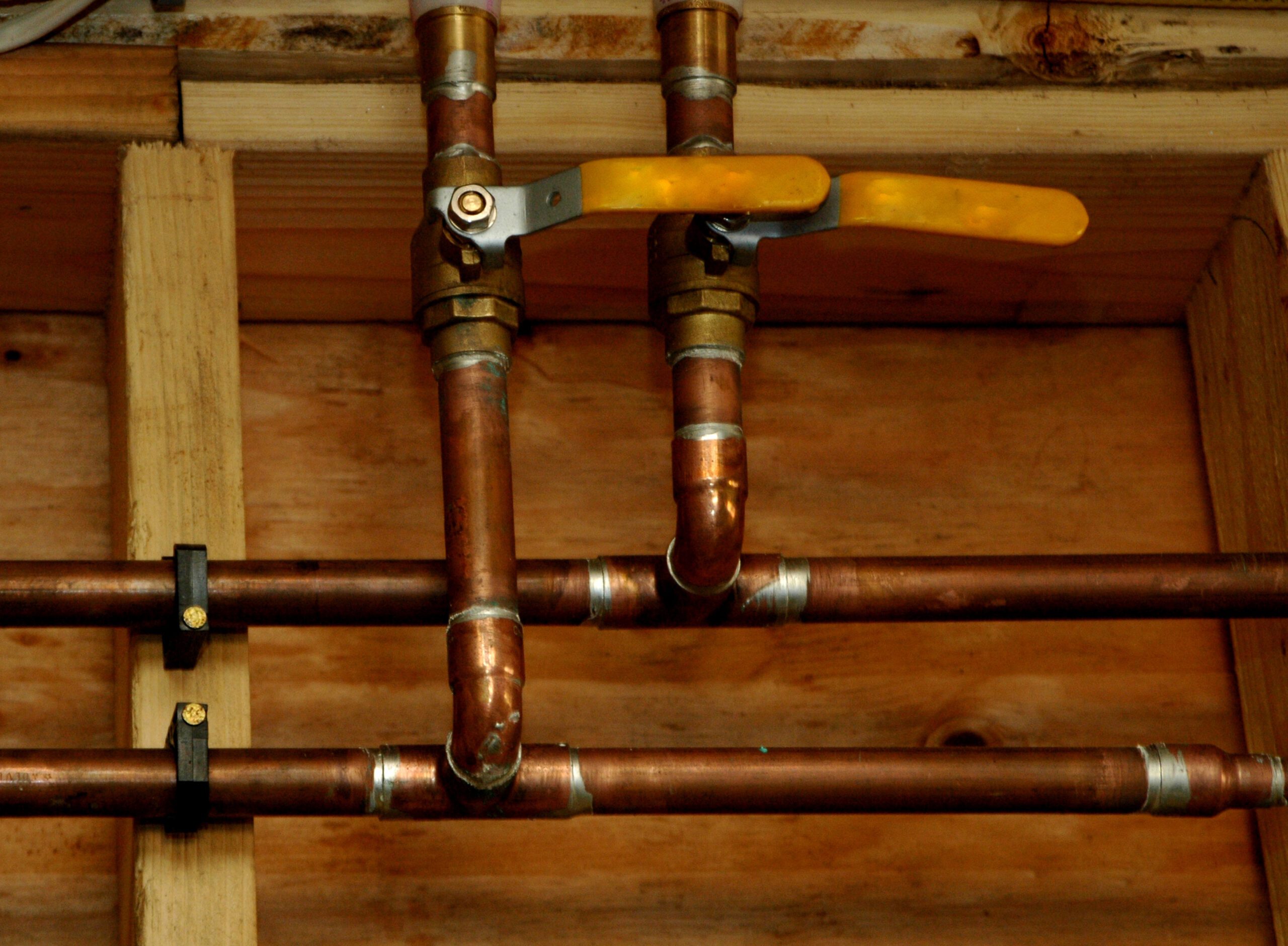 a top-down view of several aging copper pipes that are part of a residential plumbing system